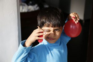 boy in blue with red balloons