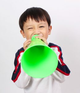 Asian boy shouting into green meaphone